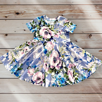 A light blue short-sleeved dress for little girls with a floral print featuring pink, white, blue, and green flowers. The dress has a full twirling skirt and a round neckline. size for ages 12 months to 12 years old. 