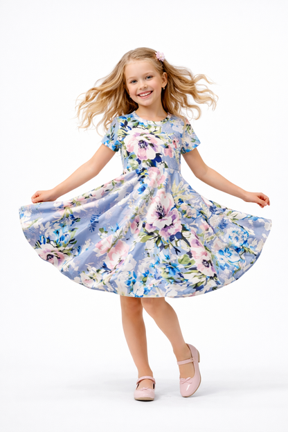 A light blue short-sleeved dress for little girls with a floral print featuring pink, white, blue, and green flowers. The dress has a full twirling skirt and a round neckline. size for ages 12 months to 12 years old. 
